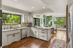 A modern kitchen with white cabinets, a wooden countertop, and a built-in dishwasher. - Tide n Timber 4BR 2.5 BA (Pebble Beach)