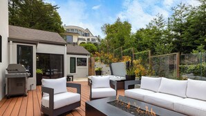 Eine Terrasse im Freien mit Feuerstelle, Sitzgelegenheiten und Grill.
