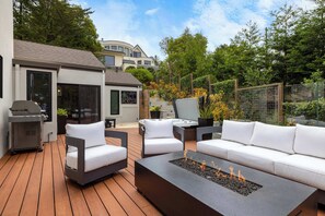 An outdoor patio with a fire pit, seating, and a grill. - Tide n Timber 4BR 2.5 BA (Pebble Beach)
