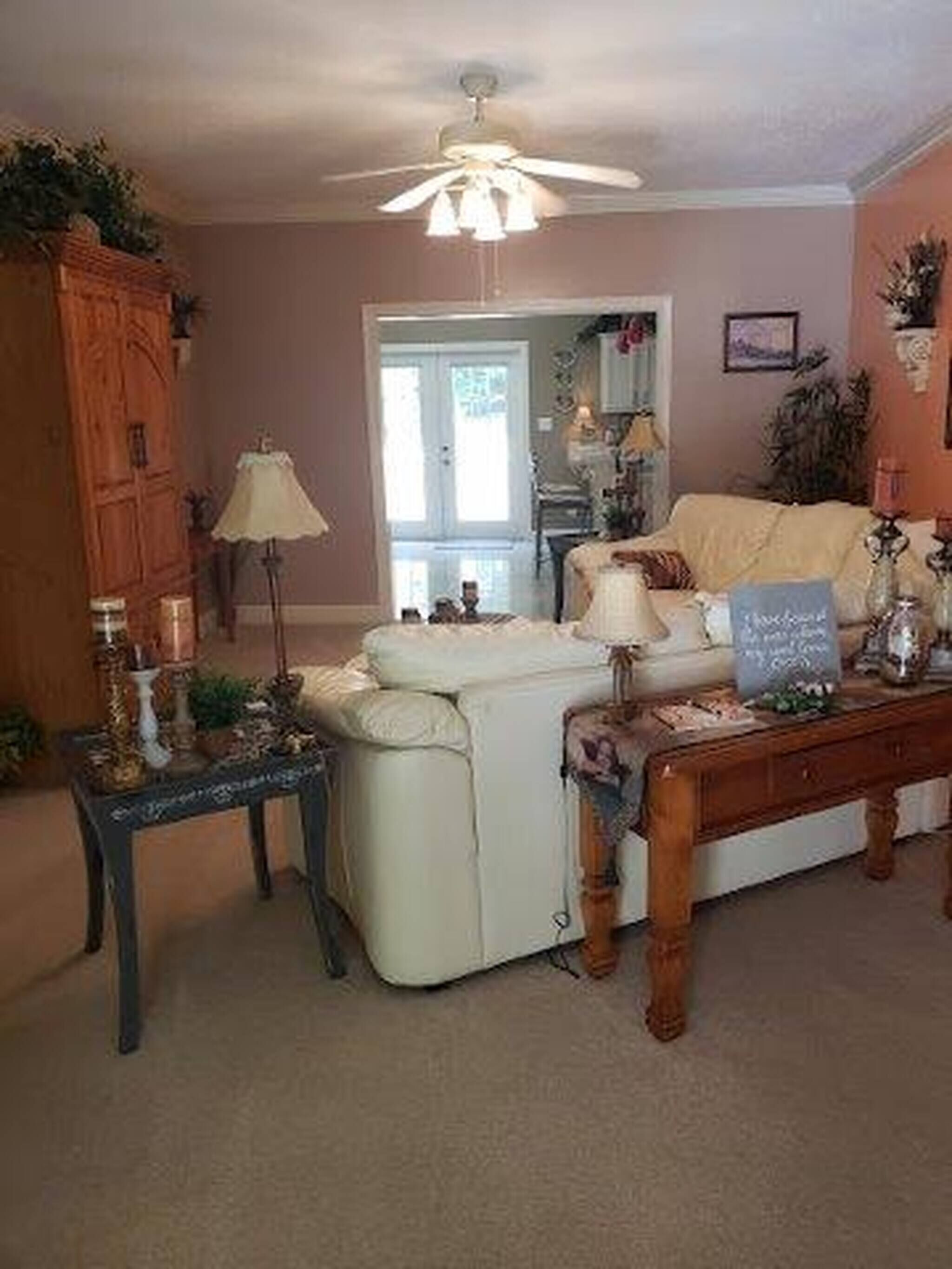 A cozy living room with a white sofa, a wooden coffee table, and a ceiling fan.