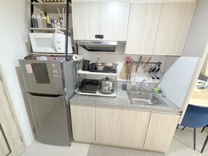 Eine kleine Küche mit Kühlschrank, Mikrowelle, Herd, Spüle und Schränken.
