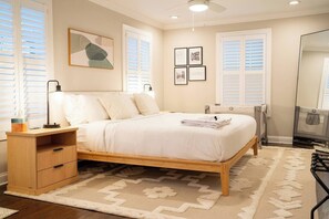 Quarto com cama, mesas de cabeceira, radiador e espelho.
