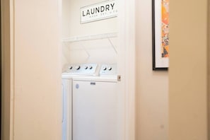 A laundry room with a sign above a washing machine and dryer. - The Mulberry at 121 Lincoln (Raleigh)
