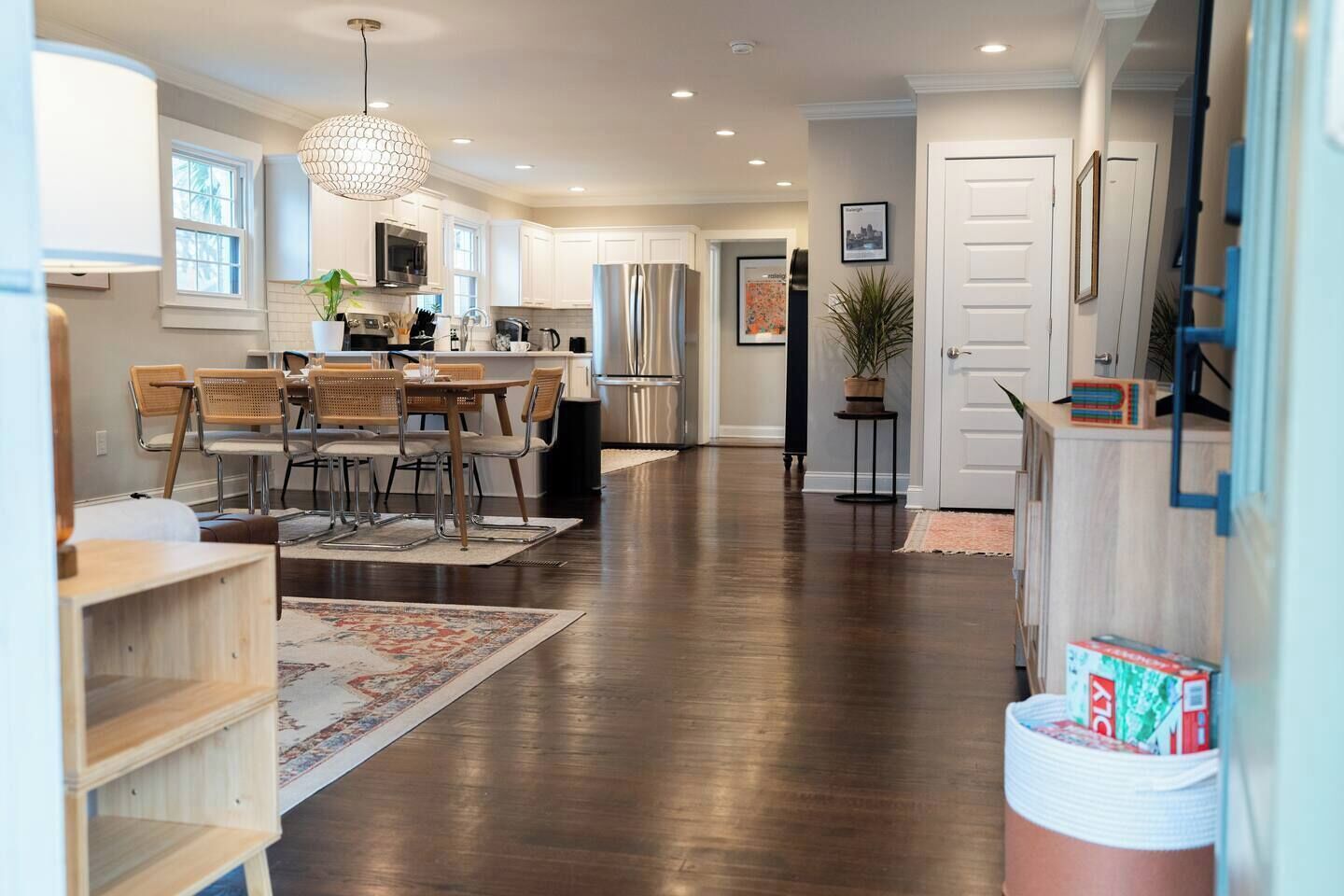 Une cuisine spacieuse équipée d’appareils modernes, un coin repas avec des chaises en bois et un couloir menant à une porte.