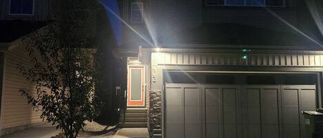 Uma garagem residencial com uma entrada de automóveis que leva a uma casa.