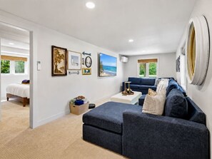 A modern living room with a sofa, a coffee table, and a bed in the adjacent room.