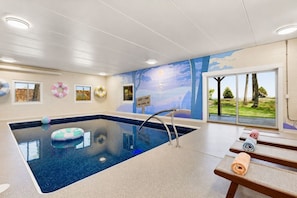 Une piscine avec vue sur l’extérieur, un espace détente avec un banc et une fresque murale.