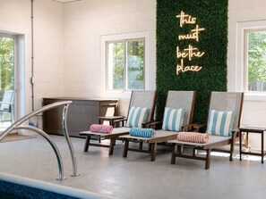 A poolside area with lounge chairs and a neon sign.
