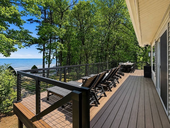 A deck with outdoor furniture, a railing, and a view of the ocean.