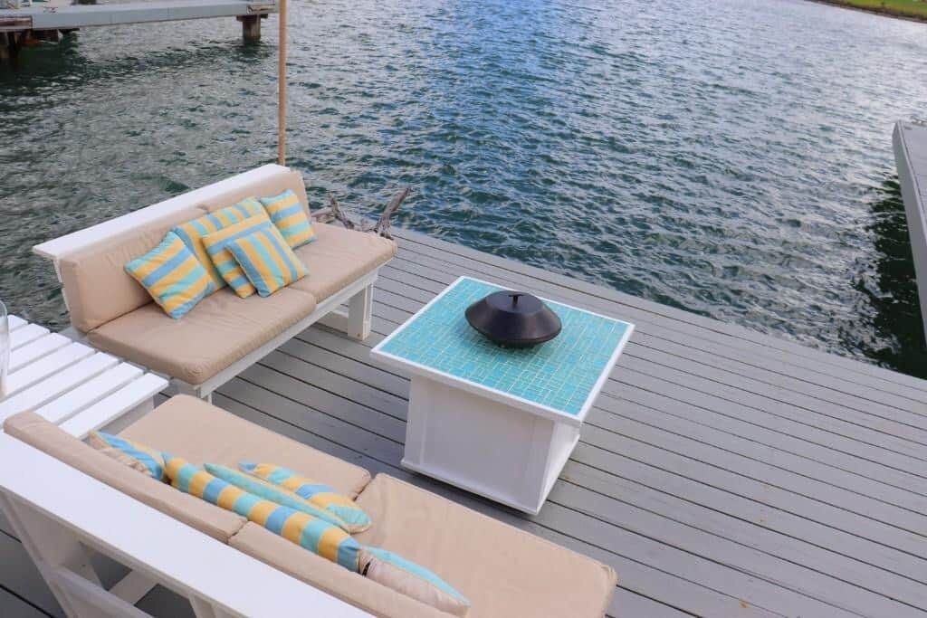 Une terrasse avec des chaises longues et une table, donnant sur une étendue d’eau.