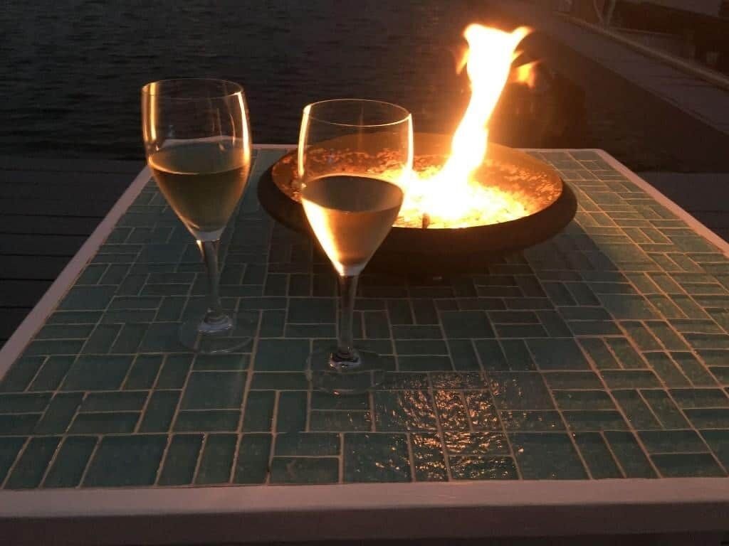 Ein Tisch mit zwei Gläsern einer klaren Flüssigkeit, möglicherweise Wein, und einem beleuchteten Feuerelement.