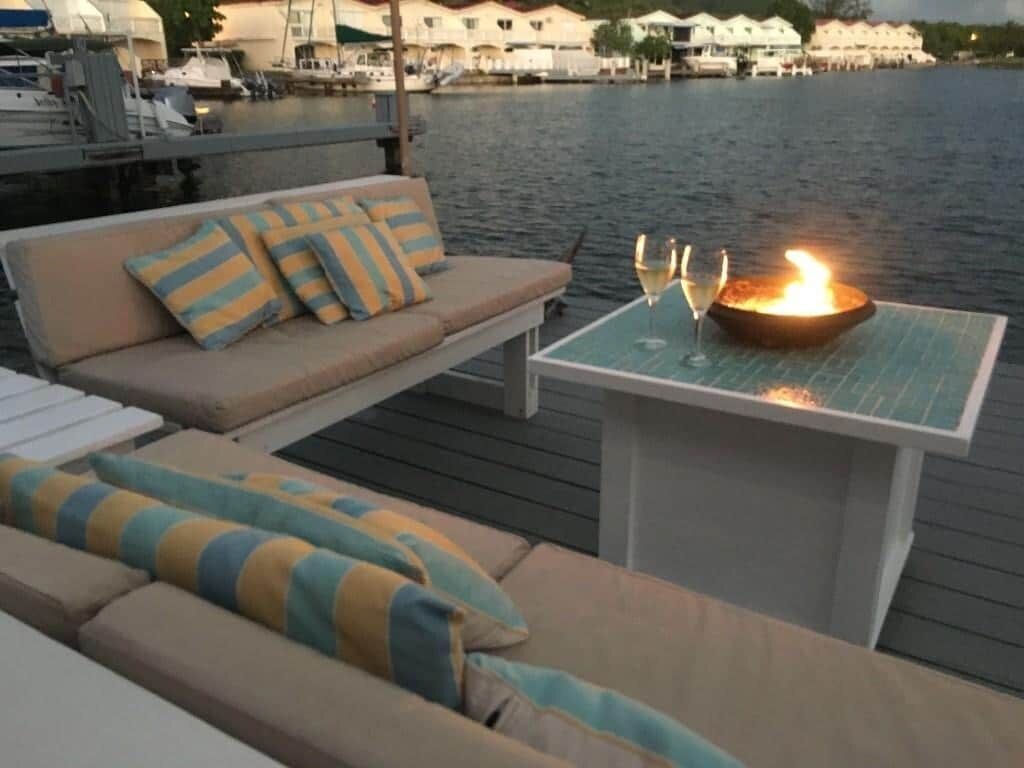 A deck with a sofa and a table, both with cushions. There is a lit candle on the table.
