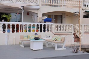 A balcony with white balustrades, a white table, and a beige sofa with striped cushions. - La Dolce Villa in Jolly Harbour Antigua (Jolly Harbour)