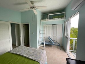 A room with a bed, a ceiling fan, a window with blinds, and a balcony with a chair. - La Dolce Villa in Jolly Harbour Antigua (Jolly Harbour)