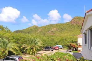 A residential area with a house, parked vehicles, and a hill in the background. - La Dolce Villa in Jolly Harbour Antigua (Jolly Harbour)