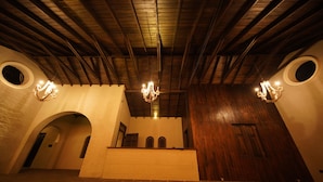 Un interior espacioso con techo alto, vigas de madera y un candelabro central.