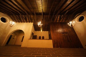 A spacious interior with a high ceiling, wooden beams, and a central chandelier.