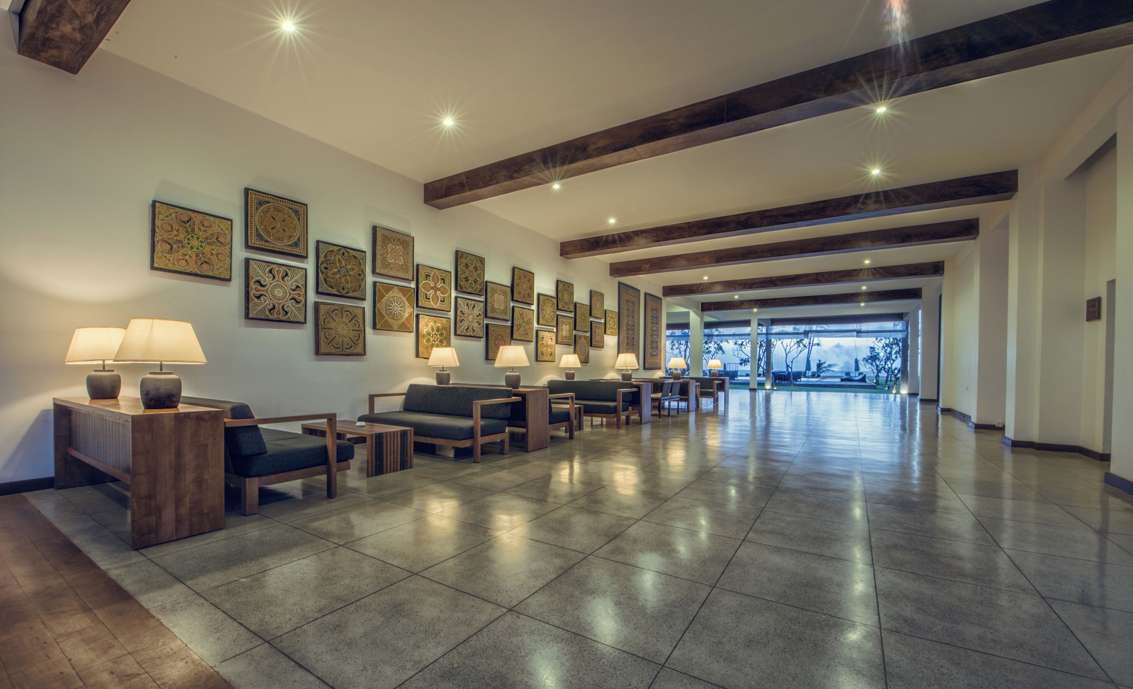 A spacious lobby with a long reception desk, multiple seating areas, and a view of the outdoors.