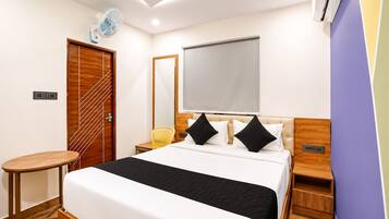Una habitación de hotel con cama, mesitas de noche, una silla, escritorio y equipo de aire acondicionado.