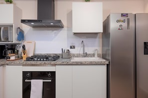 A modern kitchen with stainless steel appliances, a gas stove, a built-in oven, and a microwave. - The Skyloft Oceanfront (Punta Chame)