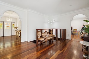 A spacious room with hardwood flooring, a wooden bench with cushioned seats, and a decorative glass door with stained glass panels. - Riezel House with Outdoor Spa and Sauna (Leura)