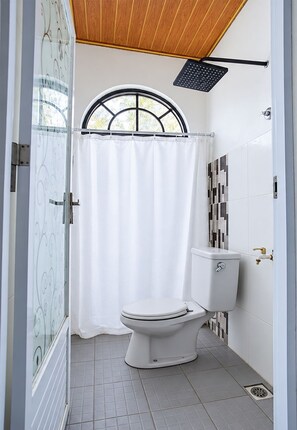 A bathroom with a toilet, shower, and a window with a curtain. - Hotel O near Mall Boemi Kedaton 1 (Bandar Lampung)