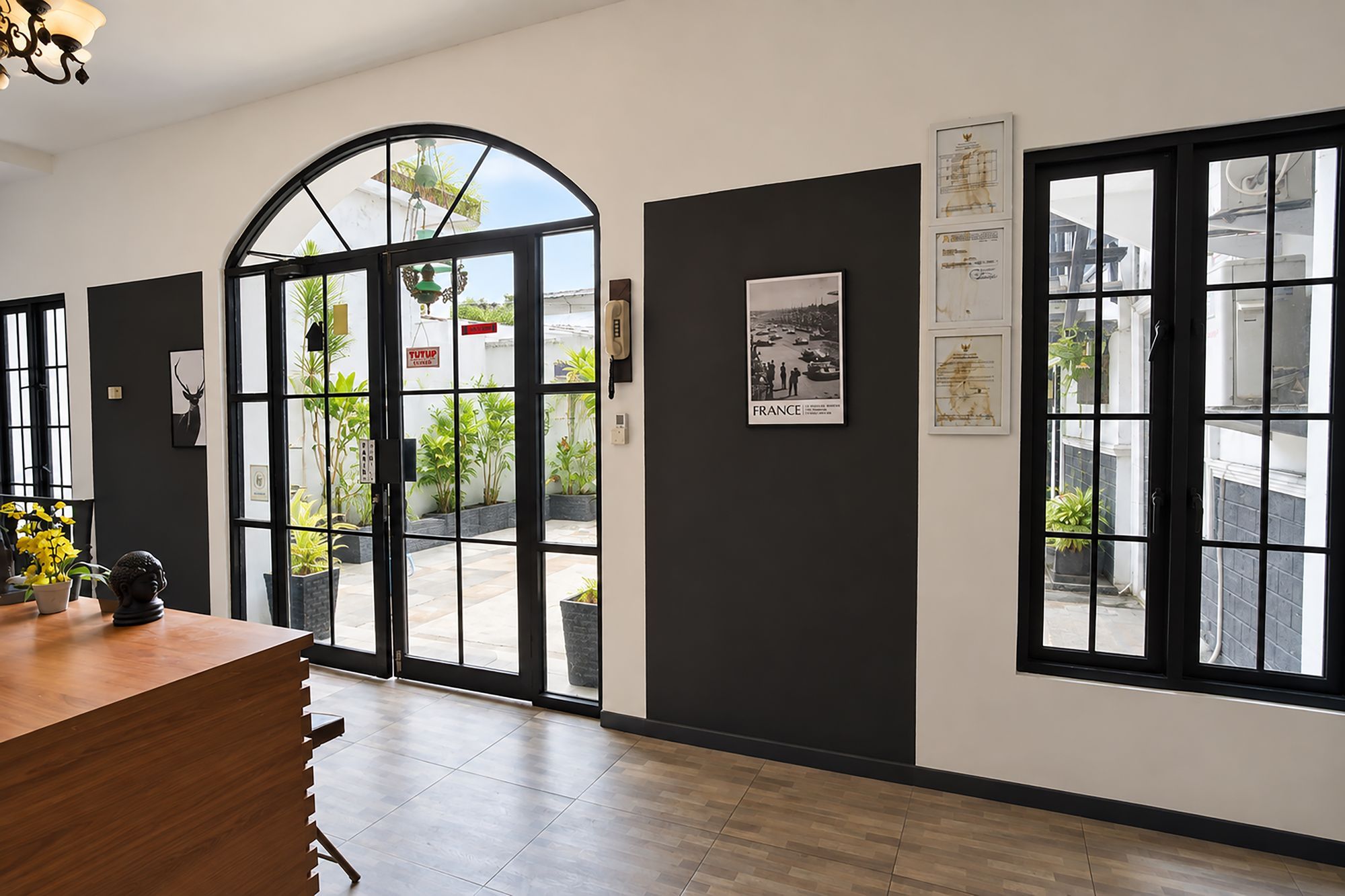 Un'area di accoglienza con una scrivania in legno, un telefono e un'ampia finestra ad arco.