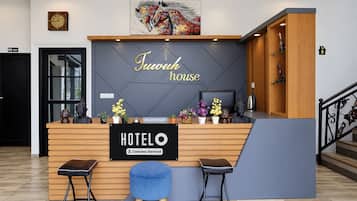 A hotel reception desk with a sign reading 'Hotel House' and a 'Hotel' sign below it. There are two bar stools, a receptionist sign, and a 'Company-Served' label.