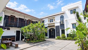 Un patio con una zona de estar, una escalera y un edificio con puerta negra.