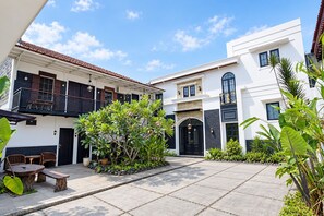 A courtyard with a seating area, a staircase, and a building with a black door. - Hotel O near Mall Boemi Kedaton 1 (Bandar Lampung)