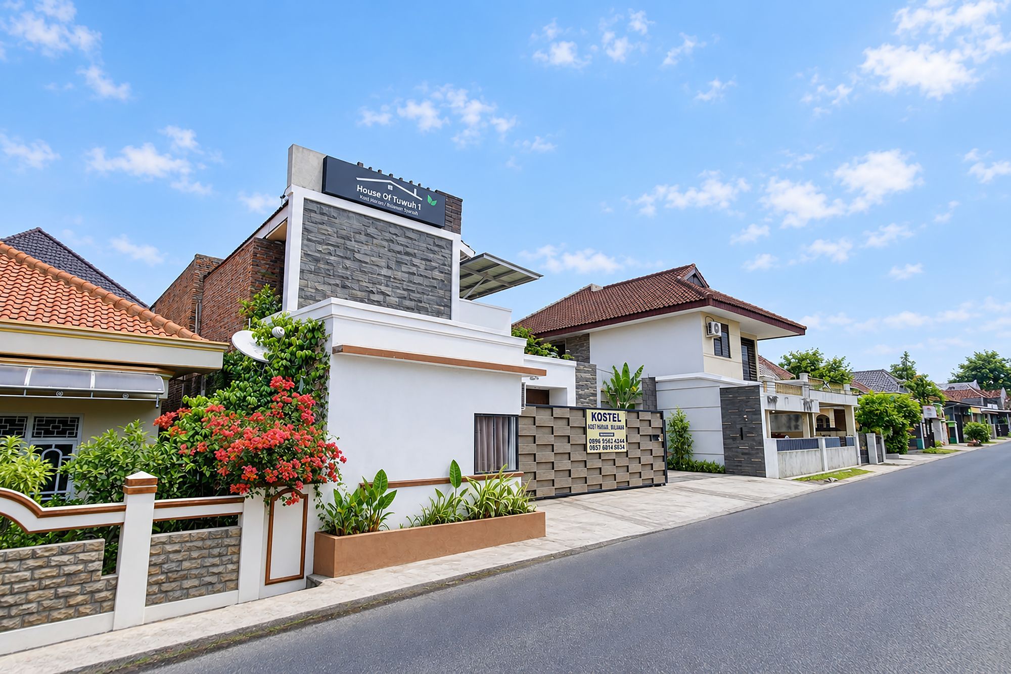 A residential street with modern houses, a clear sky, and a sign for 'House Of Tuwuh'.