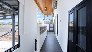 Un pasillo con piso de baldosas, techo de madera y vista al exterior.