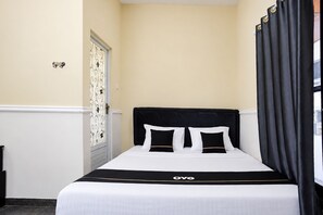 A single bed with a black headboard and white bedding, a black and white striped pillow, and a black and white striped bedspread with the word 'OYO' on it. - Hotel O near Mall Boemi Kedaton 1 (Bandar Lampung)