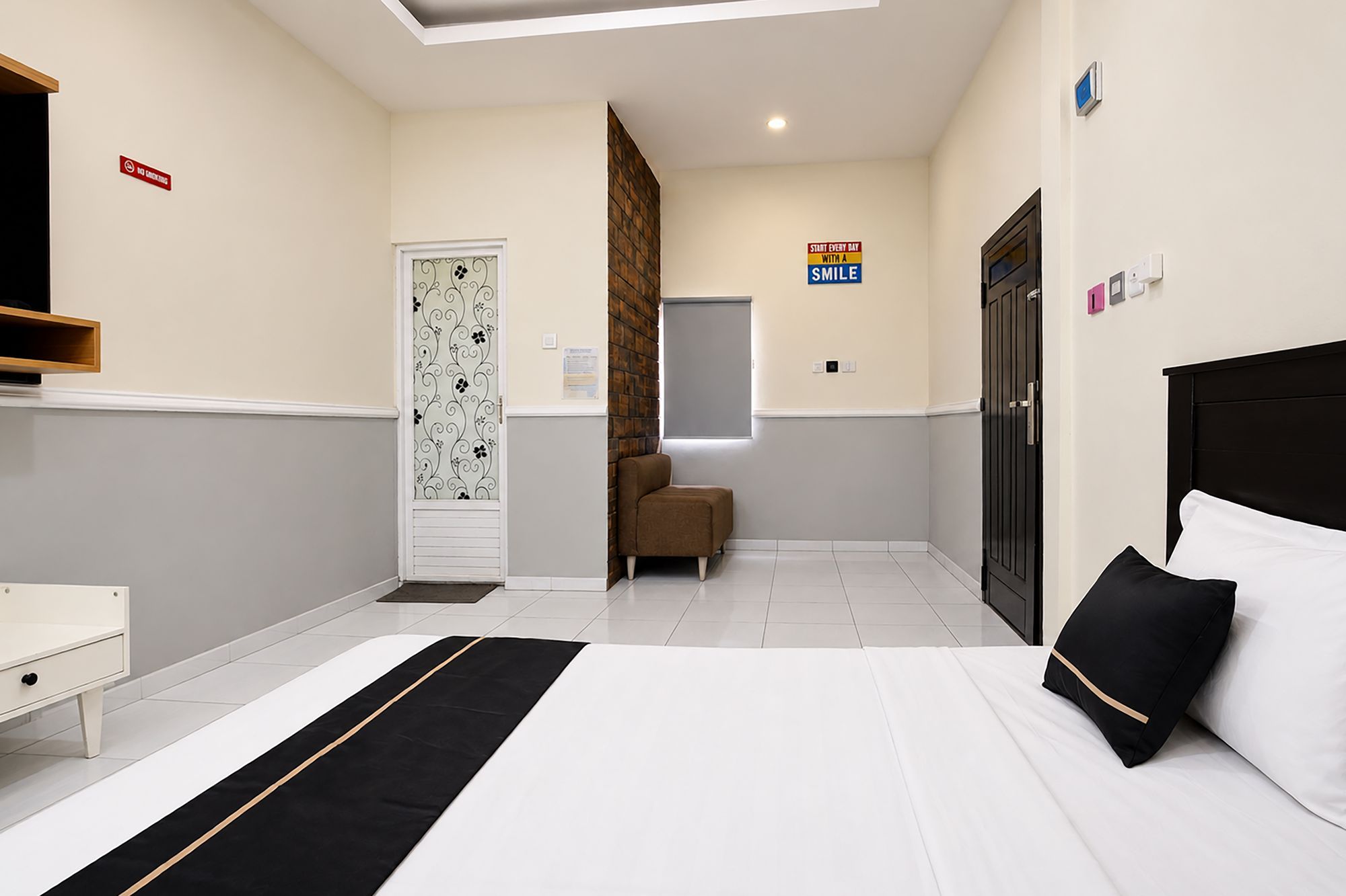 A hotel room with a bed, a chair, a desk, and a wardrobe.