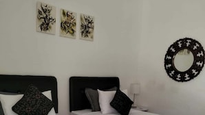 Ett hotellrum med två sängar, en rund spegel och tre konstverk på väggen.