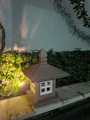 A small, illuminated model of a traditional Japanese house with a tiled roof, placed on a stone base. - Private Pool Villa Near Lovina Beach | Peaceful 2BR Tropical Escape (Buleleng)