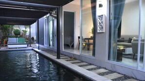 Ett modernt utomhusområde med en pool, en solstol, ett matbord och en soffa.