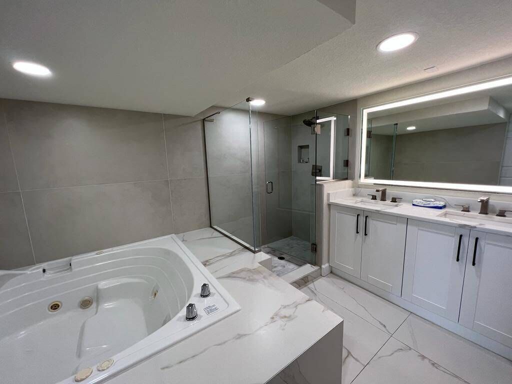 Ein modernes Badezimmer mit einer großen Badewanne, einer großzügigen Dusche und einem Waschtisch mit Spiegel.