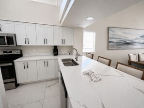 A modern kitchen with white cabinets, a marble countertop, a built-in microwave, and a coffee maker. - 2BR/2BA Westgate Villa Near Disney Resort Pools & Family Fun (Kissimmee)
