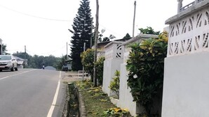 A road with a drainage ditch alongside a white wall with decorative patterns. - Sunset View Guest House (Sekondi-Takoradi)