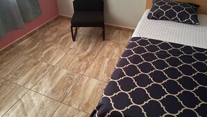 A room with a bed, a chair, and a tiled floor. - Sunset View Guest House (Sekondi-Takoradi)