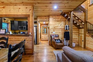 A wooden interior with a kitchen, dining area, and a staircase.