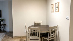 A dining area with a round table and six chairs, a wooden ceiling beam, and a tiled floor. - Mt. Fisher Legal Guest Suite –Private Entrance. (Cranbrook)
