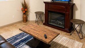 A living room with a television on a stand, a fireplace, a sofa, and a coffee table. - Mt. Fisher Legal Guest Suite –Private Entrance. (Cranbrook)