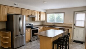 A modern kitchen with a central island, stainless steel appliances, and wooden cabinetry. - Mt. Fisher Legal Guest Suite –Private Entrance. (Cranbrook)