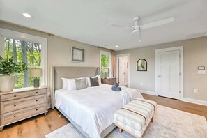 A bedroom with a large bed, bedside tables, a ceiling fan, and a view of trees through the window. - New Family Retreat-Sleeps24-Theatre-Dock-HotTub (Mineral)