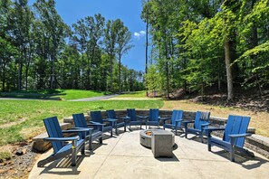 An outdoor seating area with blue Adirondack chairs arranged around a circular fire pit. - The Gathering Place (Mineral)