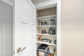 A kitchen pantry with shelves containing a coffee maker, a blender, and storage containers. - The Gathering Place (Mineral)