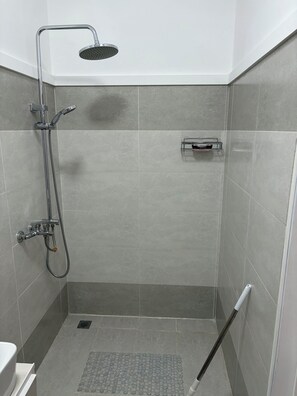 Una ducha con tres cabezales de ducha manuales.