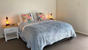 A bedroom with a bed, two bedside lamps, a nightstand with a drawer, and a wall-mounted picture.